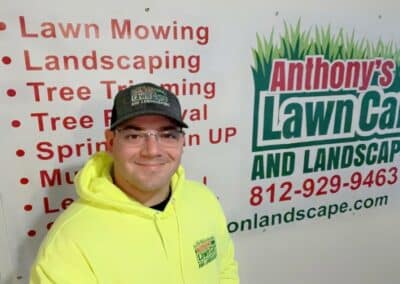 Anthony of Anthony’s Lawn Care Landscaping and Tree Removal is smiling in front of one of his signs