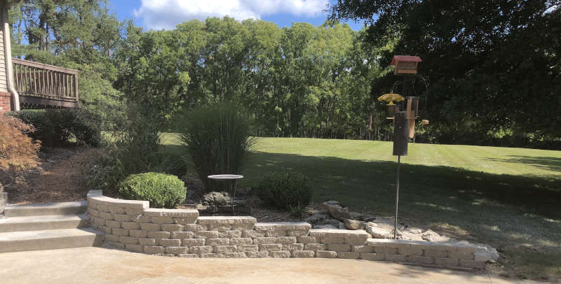 A backyard with a retaining will built by Anthony's Lanscaping in Bloomington IN